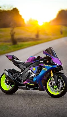 a purple and blue motorcycle parked on the side of the road at sunset or sunrise