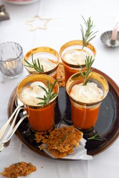 four small cups filled with sauces and garnished with rosemary on a plate