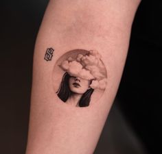 a woman's arm with a tattoo on it that has clouds coming out of her head