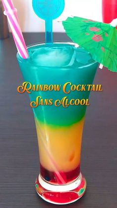 there is a rainbow cocktail with two straws on the top and an umbrella in the middle