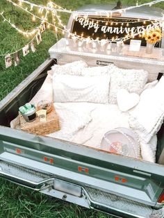 an open truck bed sitting on top of a lush green field next to a string of lights