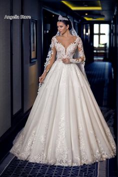 a woman in a wedding dress is standing on the hallway with her hands behind her back