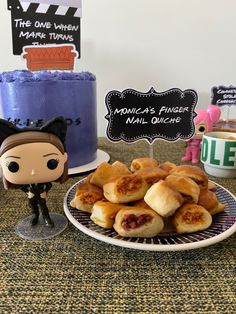 a table topped with lots of pastries next to a cake and toy figurines