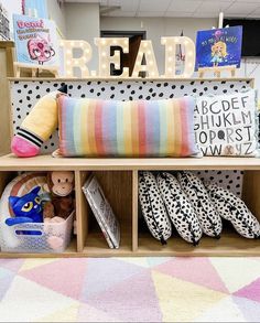 a book shelf filled with lots of books and stuffed animals next to a reading sign