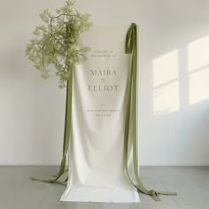 a white chair with a green ribbon tied around it and a bouquet of flowers in the back