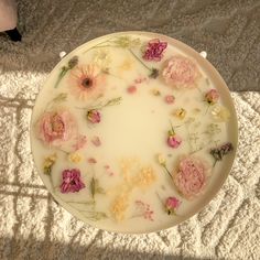 a white plate with flowers on it sitting on the floor next to a person's feet