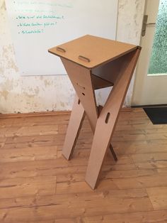 an open cardboard box sitting on top of a wooden floor next to a whiteboard