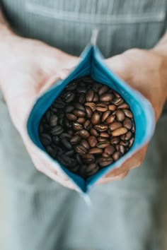 a person holding out their hands with some beans in it