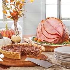 a table set for thanksgiving dinner with ham and other foods on it, along with plates and utensils