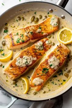 two fish fillets in a pan with lemons and capers