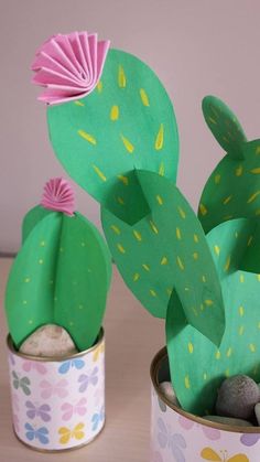 some paper cactus plants are sitting in small tins