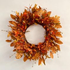 a wreath with leaves and berries hanging on the wall