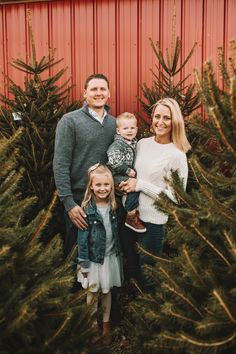 a family standing in front of christmas trees