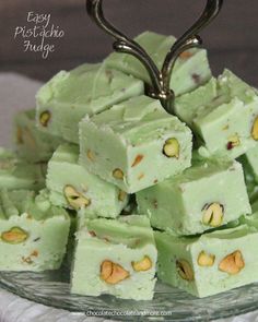 a glass plate topped with green fudge squares covered in nuts and pistachio