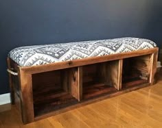 a wooden bench sitting on top of a hard wood floor next to a blue wall