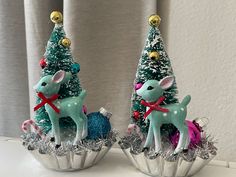 two small christmas trees with deer figurines in them