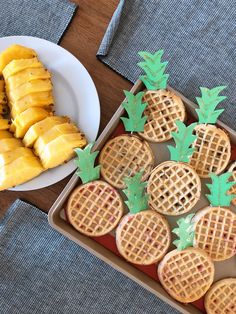 some pineapples and waffles are on a tray next to a plate of bananas