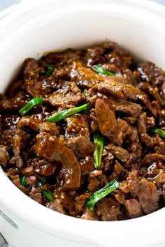 a close up of a bowl of food with meat and green onions in the middle