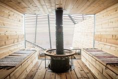 the inside of a wooden cabin with three beds and a wood burning stove in it