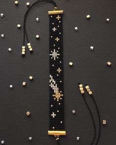 a black beaded bracelet with gold and white crosses on it, surrounded by tiny cubes