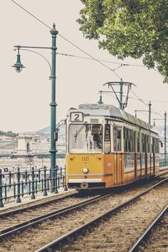 a yellow and white train traveling down tracks next to a street light on a cloudy day