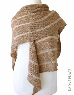 a white mannequin wearing a brown knitted shawl with stripes on it