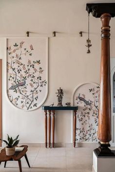 a living room with paintings on the wall and two tables next to each other in front of them