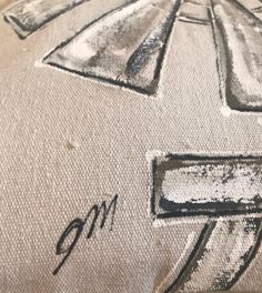 close up view of an embroidered pillow with numbers and arrows on the front, in white linen