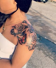 a woman with a butterfly and roses tattoo on her arm is standing in the street