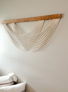 a white bed sitting under a wooden shelf next to a wall mounted art piece on the side of a wall