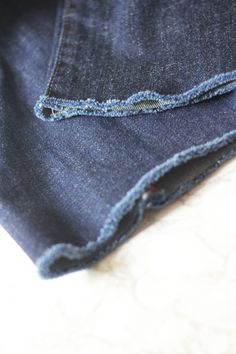 a pair of blue jeans with holes in the back and side pockets, on a white surface