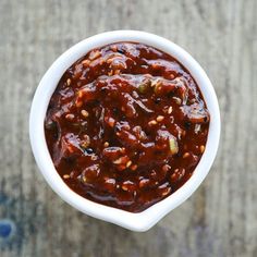 a white bowl filled with chili sauce on top of a wooden table