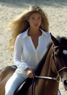 a woman riding on the back of a brown horse