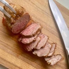 a piece of meat on a cutting board next to a knife