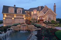 a large house with a fountain in the front yard and landscaping around it at night