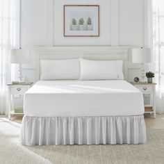 the bed is made with white sheets and ruffled bedskirt, along with two nightstands