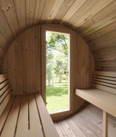 the inside of a sauna with wooden walls and windows looking out onto a grassy area