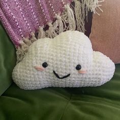 a crocheted cloud pillow sitting on top of a green couch