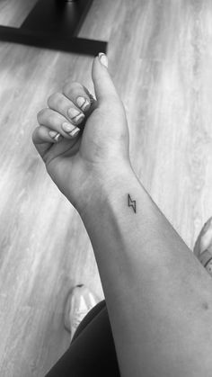 a woman's arm with a small arrow tattoo on the left side of her wrist