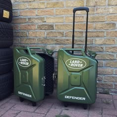 two green suitcases sitting next to each other on the side of a brick wall