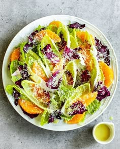 a salad with oranges, lettuce and parmesan cheese