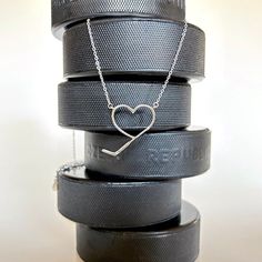 a stack of black tires with a heart on the top and two silver chains attached to them