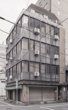 an apartment building with many windows and balconies on the top floor, next to a street corner