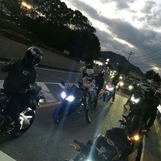 several motorcyclists are riding down the street at night with their lights on