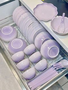 purple dishes and plates are stacked in a dishwasher drawer on the counter top