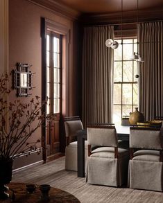 a dining room with chairs and a table in front of a window that has drapes on it