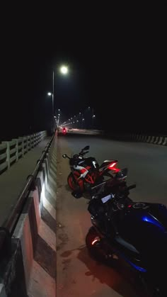 two motorcycles parked next to each other on the side of a road at night time