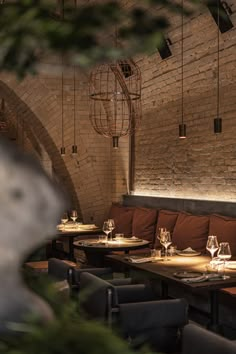 an empty restaurant with wooden tables and brown chairs, brick walls and exposed ceilinging