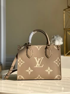 Inspired by Louis Vuitton’s famous Sac Plat from 1968, the Onthego PM tote is fashioned in Monogram Empreinte leather, embossed with a Giant Bicolor Monogram pattern. This smaller version of the original Onthego fits essentials such as an iPad Mini. Articulated top handles and an adjustable removable strap offer a variety of carry options. Detailed Features 25 x 19 x 11.5 cm (Length x height x width ) Tourterelle Beige/Cream Embossed grained cowhide leather Grained cowhide leather trim Microfibe Tas Louis Vuitton, Louis Vuitton Onthego, Sac Louis Vuitton, Tas Bahu, Luxury Bags Collection, Louis Vuitton Crossbody, Monogram Pattern, Chanel Deauville Tote Bag, Coach Bag