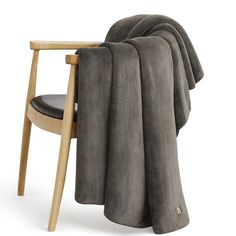 a chair with a blanket on top of it next to a wooden chair and arm rest